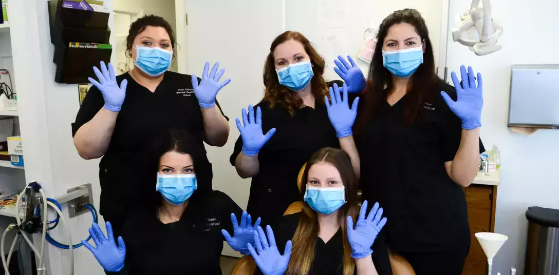 students posing for a group photo with gloves and masks on in dental office